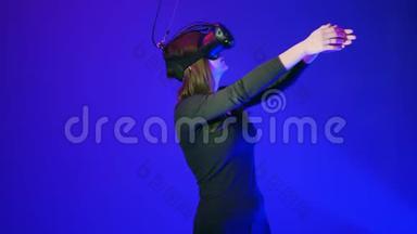 年轻女子在VR耳机玩得开心，玩互动电子游戏。 蓝色背景下的虚拟现实头盔